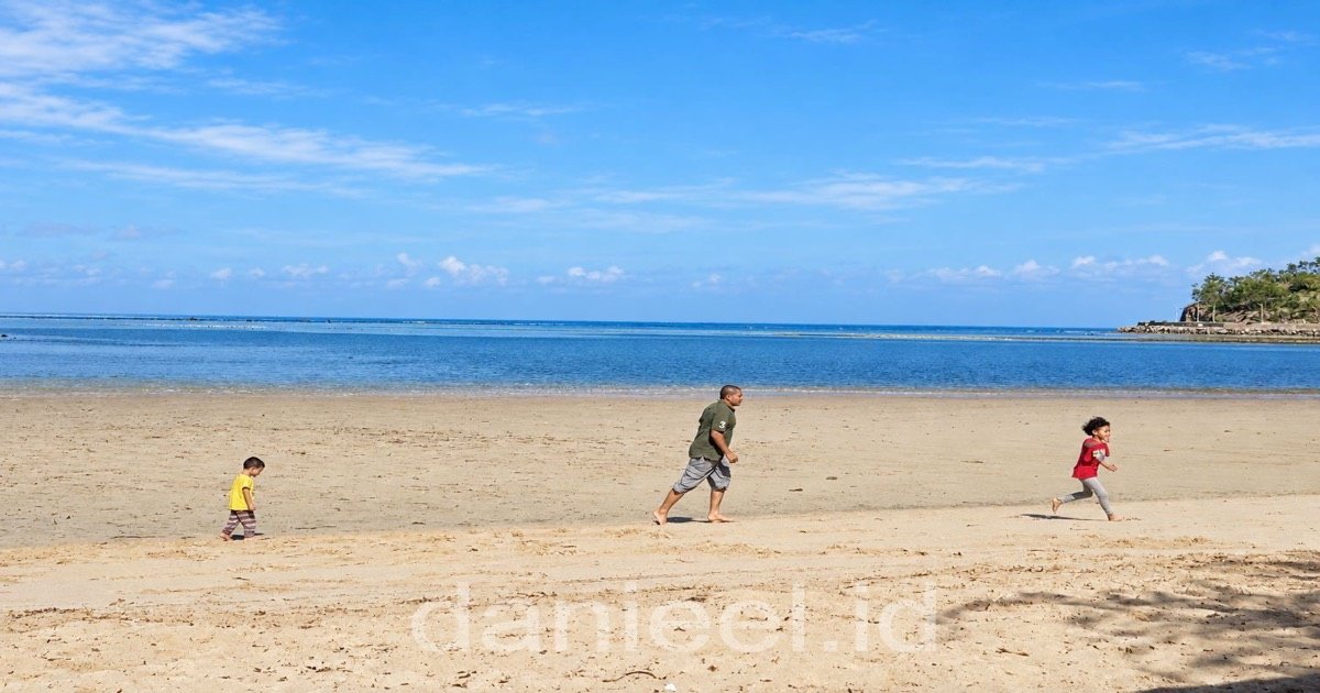 seorang ayah berlari di pantai dengan kedua anaknya
